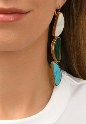 Les boucles d'oreilles pendantes dorées présentent trois pierres ovales : blanche, verte et turquoise, avec des détails marbrés, suspendues à un design de crochet simple.