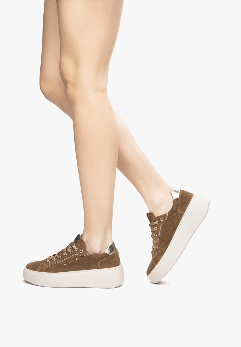 Sneaker in suede marrone con una spessa suola piattaforma bianca, caratterizzate da accenti metallici e punta rotonda, design con lacci e cuciture a contrasto.