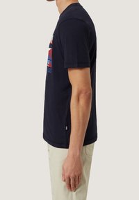 Mörkblå t-shirt i bomull med korta ärmar, med ett grafiskt tryck i rött och blått. Klassisk rund halsringning och normal passform.