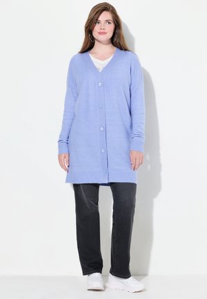 Cardigan bleu clair avec un col en V, fermeture à boutons, poignets et ourlet côtelés. Associé à un jean foncé et des baskets blanches, sur fond blanc.