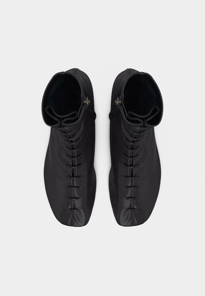 Μαύρα δερμάτινα μποτάκια αστραγάλου με κεντρικά κορδόνια και πλευρικά φερμουάρ, απεικονιζόμενα από πάνω σε απλό λευκό φόντο.