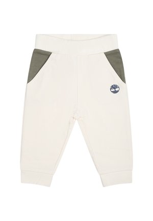 Pantalons de survêtement couleur crème avec poches latérales vertes, taille élastique et logo brodé. Tissu doux avec une texture lisse.