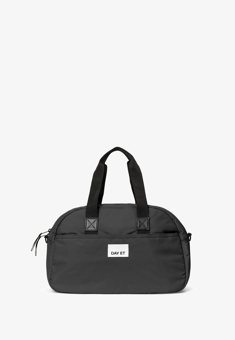 Musta duffel-laukku, jossa on kaksi tukevata kahvaa ja vetoketju, etuosassa valkoinen etiketti, jossa lukee "DAY ET". Yksinkertainen, moderni muotoilu.