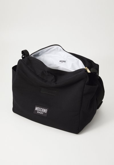 Black fabric diaper bag with a smooth finish, zip closure, and white interior. Features Moschino Baby logo patch on the front. Adjustable strap included.