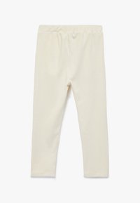 Krämfärgade leggings gjorda av mjukt, elastiskt material med midja av resår och en figurnära design, som har en slät yta.