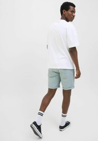 Ljust blå shorts med upprullade fållar, i kombination med en vit t-shirt. Svarta sneakers och randiga strumpor fulländar outfiten.