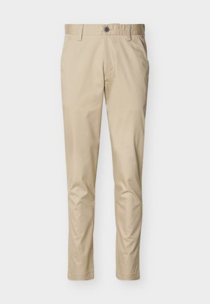 Beiget, kapeat housut, joissa on vyölenkit, napillinen kiinnitys, sivutaskut ja ommeltu helma, aseteltuna tasaisesti vaalealle taustalle.