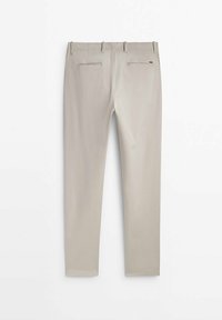 Pantalon beige coupe slim vu de dos avec deux poches passepoilées et des passants de ceinture sur fond blanc.