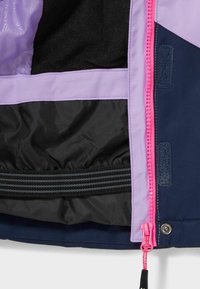 Fialovo-modrý kabát s černou podšívkou, vybavený jasně růžovým zipem, proužkovaným elastickým pásem a textilními detaily.