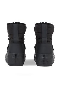 Botas de invierno negras con parte superior acolchada y borde de piel sintética, cuentan con una suela de goma y un sutil logotipo en el talón.