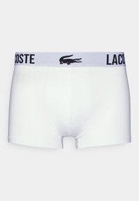 Boxer shorts blancs en coton doux, dotés d'une ceinture élastique noire et grise avec le logo "LACOSTE" et un emblème de crocodile.