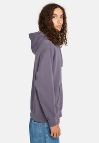 Kapuzensweatshirt in gedämpftem Lila. Aus weichem Material, mit einer Kängurutasche, gerippten Bündchen und Saum. Einfaches Design ohne sichtbare Logos.