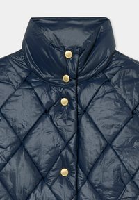 Tmavě modrá prošívaná bunda s vysokým límcem a zlatými cvoky. Vyrobena z lesklého, texturovaného materiálu s diamantovým vzorem.