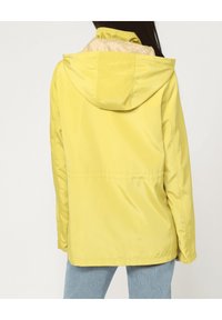 Chubasquero amarillo con capucha, textura suave, con un forro estampado. La vista posterior muestra un diseño simple, detalles de costuras y un corte relajado.
