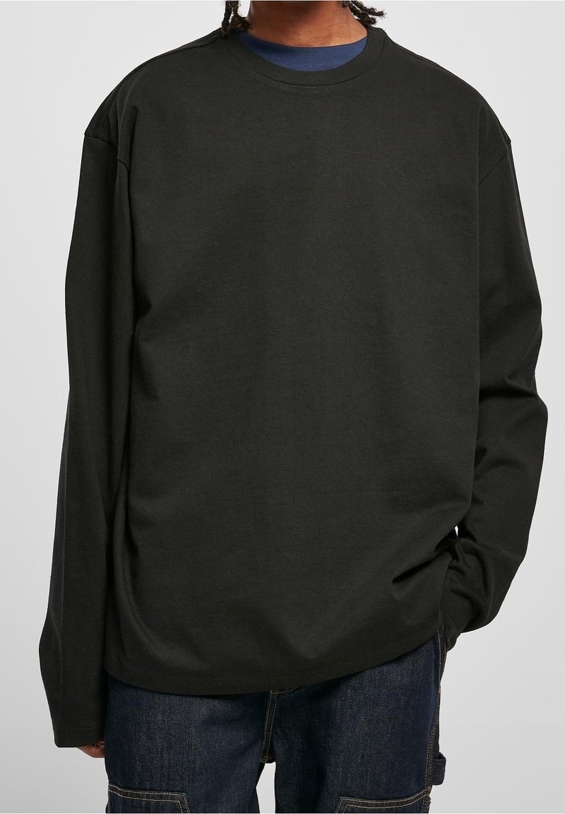 Black long-sleeve t-shirt in cotton with a crew neckline, relaxed fit, and dropped shoulder seams, worn over a navy shirt.