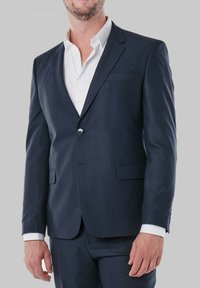 Veste de costume bleu marine en tissu lisse, à fermeture à un bouton, avec des revers crantés et des poches à rabat à l'avant, portée sur une chemise blanche.