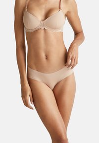 Reggiseno beige chiaro con rifiniture in pizzo, coppe imbottite, spalline regolabili e culotte senza cuciture abbinate, entrambi realizzati in tessuto morbido.