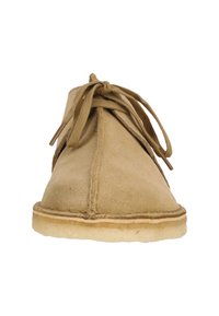 Beige mokasin kengät pyöreällä varpalla, nauhakirjontasuunnittelu ja tekstuuripinta. Varustettu vaalean värisellä kumipohjalla.