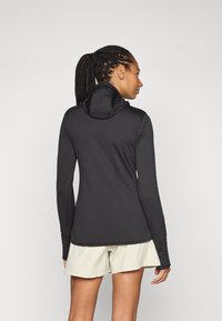 Zwart langwerpig top met een capuchon, gemaakt van gladde stof en een aansluitend ontwerp. Gecombineerd met lichtgekleurde shorts, wat een sportieve uitstraling benadrukt.