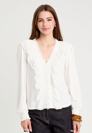 Weiße Bluse mit gerafftem Frontdetail, langen Ärmeln mit frilly Bündchen und einem V-Ausschnitt. Der Stoff ist glatt und leicht.