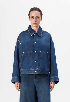 Denimjakke i mørkeblå, med to frontlommer, sølvnagler på kragen og en avslappet, oversized passform.