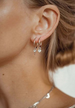 Silver hoop earrings featuring heart and key charm pendants, showcasing a polished finish and delicate design elements.
