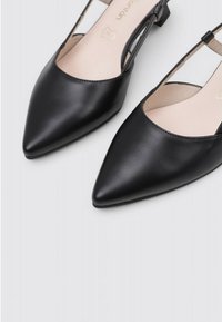 Ballerines à talon bas en cuir noir à bout pointu, avec une texture lisse et un design à côté découpé.