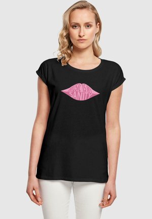 Schwarzes T-Shirt mit einem pinken Lippen-Graphic und dem Text "MUSIK IST MEINE SEELENRUHE". Der Stoff ist weich, und das Design ist einfach, aber auffällig.