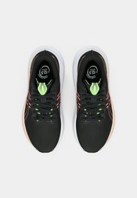 Ténis desportivos pretos com parte superior texturizada, detalhes em verde néon e sola exterior branca. Apresentam atacadores pretos e um design único no calcanhar.