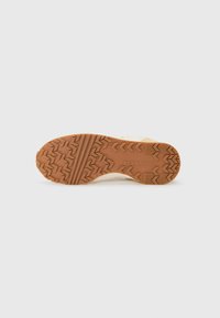 Talpa bej de sneaker cu un outsole din cauciuc maro texturat, având un model zigzag și cuvântul "CONVERSE" embossat.
