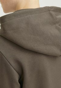 Felpa con cappuccio marrone caratterizzata da una tessitura del tessuto liscia, un design semplice e una vestibilità comoda, che mette in evidenza i dettagli delle cuciture e la forma del cappuccio.