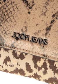 Brun orm-skinsmönstrad material med mörkare fläckar, med en leopardmönstrad nedre del. Svart "JOOP! JEANS"-logotyp närvarande.