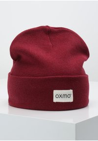 Maroon beanie hat made of soft knit material, featuring a turned-up cuff and a rectangular label with "OXMO" stitched on it.