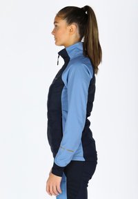 Blue and navy hybrid jacket with a high collar, quilted front, smooth sleeves, and gold accent details. Zippered front closure.
