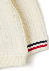 Kabelstrickpullover in Creme mit gerippten Bündchen in Rot, Weiß und Marineblau. Weiche Textur mit klassischem Design.