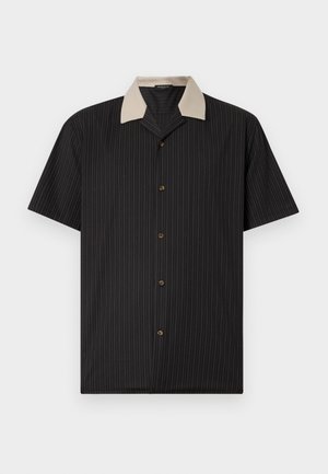 Majica s kratkimi rokavi v črni barvi z navpičnimi črtami, ki ima bež ovratnik in sprednje gumbe. Narejena iz lahkotnega blaga z gladko teksturo.