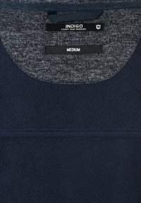 Sudadera con capucha de forro polar azul marino que presenta un interior del cuello gris jaspeado, tela texturizada y una etiqueta que dice "INDIGO" y "MEDIUM."