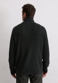 Pull en tricot vert foncé avec un col haut, texture côtelée et manches longues. Offre une coupe décontractée et des détails subtils à l'ourlet inférieur.