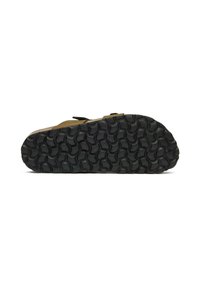Sandal sole with textured black rubber, featuring circular patterns for grip. Upper in a muted yellow-green color, minimalist design.