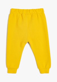 Lyst gul ribbet bukser til småbørn med elastisk talje og opsmøgte ankler på en hvid baggrund.