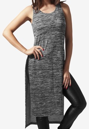 Vestido tipo tank en mezcla de tonos grises con espalda larga, escote redondeado y aberturas laterales, combinado con pantalones negros ajustados. Textura de tela suave.