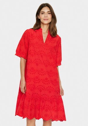 Red, short-sleeve dress with a V-neck, featuring a scalloped hem and raised floral embroidery patterns throughout the fabric.
