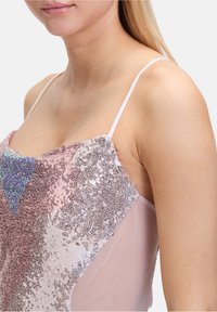 Débardeur orné de sequins, en tissu léger rose clair, avec une coupe ajustée et des fines bretelles. Motifs texturés en argent et bleu.
