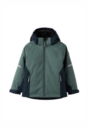Waterdichte jas in groen en marineblauw. Voorzien van een rits aan de voorkant, een verstelbare capuchon, reflecterende accenten en elastische manchetten voor een veilige pasvorm.