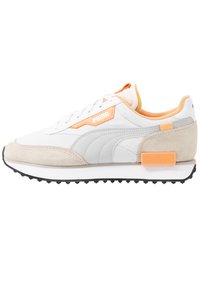 Baskets Puma blanches et gris clair avec avant en daim beige, accents orange et semelle noire en caoutchouc texturée, vue latérale sur fond blanc.