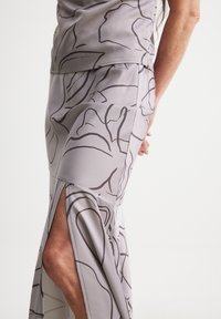 Light grey dress with abstract dark lines, fitting closely with a thigh-high slit on one side. Smooth texture, elegant design.