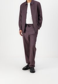 Two-piece outfit featuring a light purple, pinstriped jacket and matching pants, with an elastic waistband and black shoes.