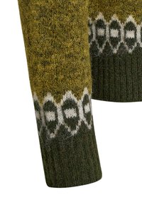 Stickad tröjärm i gröna och gula nyanser, med ett vitt geometriskt mönster nära ärmslutet. Mjuk, texturerad ulltyg.