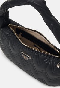 Borsa a tracolla nera trapuntata con manico attorcigliato, dotata di un logo triangolare dorato e di un'apertura con zip che rivela un interno beige con tasche.