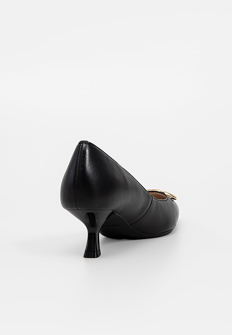 Zapato de tacón kitten de cuero negro con un pequeño tacón curvado y detalle de hebilla dorada en la parte superior delantera, mostrado desde una vista trasera en ángulo.